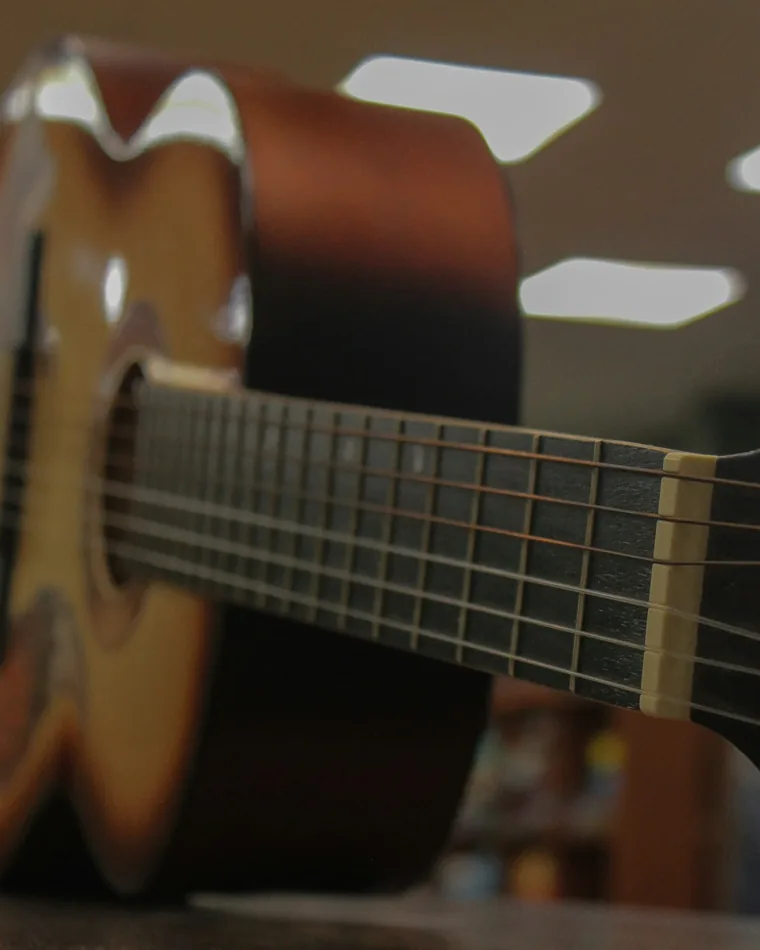 Detalle de la tapa y el puente de una guitarra acústica de madera clara